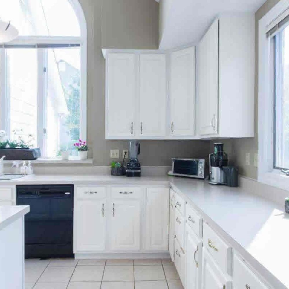 <span class="uk-h4">A bright kitchen with white cabinets, a large window above the sink, and various kitchen appliances on the counters, creating a clean and airy atmosphere.</span>